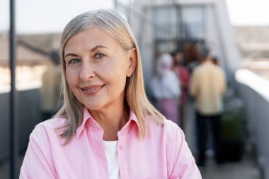 Gülümseyen mutlu son sınıf kadınının portresi günlük giysiler giyip açık havada fotokopi çekilen kameraya bakıyor. Reklam kavramı