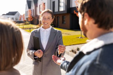 Emlakçı, modern evlerin dışındaki yeni ev sahiplerinin anahtarlarını veriyor.