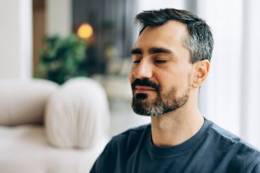 Adam sakin ve düşünceli, gözleri kapalı, meditasyon yapıyor.