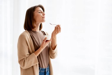 Yoğurttan hoşlanan bir kadın, sağlıklı ve sıradan bir yaşam tarzından zevk alıyor.