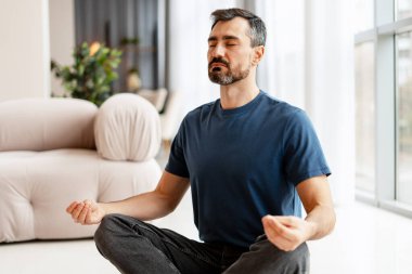 Yogada meditasyon yapan bir adam gözleri kapalı, elleri Mudra 'da, dengeyi ve huzuru buluyor.
