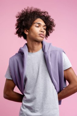 Yakışıklı, çekici, şık kapüşonlu bir Latin erkek pembe arka planda yalnız poz veriyor. Moda modeli stüdyoda poz veriyor. Reklam kavramı