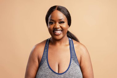 Bej arka planda izole edilmiş kameraya bakan gülümseyen, pozitif Afrikalı Amerikalı kadın portresi. Reklam, diş bakımı konsepti