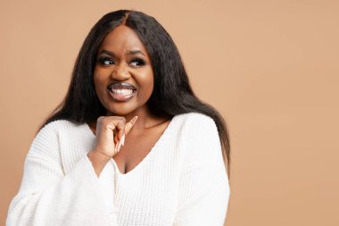 Beyaz kazak giyen ve bej arka planda izole edilmiş güzel, büyük boy Afro-Amerikan kadın portresi. Alışveriş konsepti