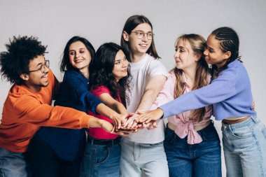 Young friends showing collaboration and support with their hands stacked, celebrating success