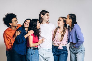 Happy group of diverse young friends smiling, embracing each other, and having fun at a social gathering