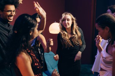 Genç ve çeşitli insanlar canlı bir gece hayatını kutluyor, gülüyor ve müziğe geçiyorlar.