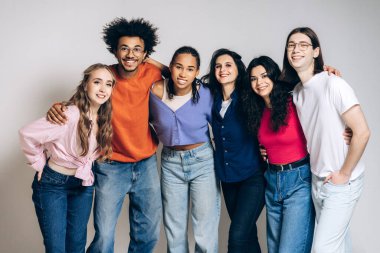 Diverse group of smiling young adult friends standing arm in arm, showing togetherness, community, and support against a white background, representing connection and happiness. Friendship concept