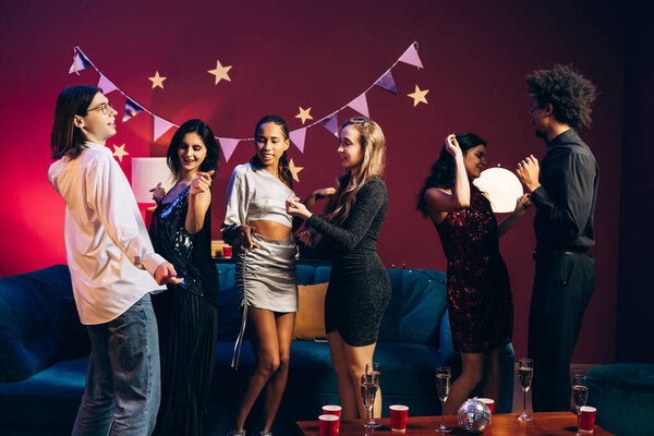 Group of diverse young adults enjoying a lively house party, dancing and socializing