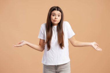 Elleri havada omuz silken, şüphe, şaşkınlık ve bilgisizlik gösteren genç bir kadın.