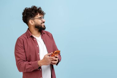 Genç adam gülümsüyor ve başka tarafa bakıyor, elinde bir cep telefonu, yeni fikirler ya da kavramlar düşünüyor.