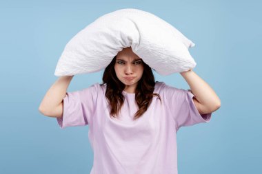 Başının üstünde yastık tutan kadın, sinir bozukluğu, ses ya da uyku sorunları yüzünden hayal kırıklığı yaşıyor.