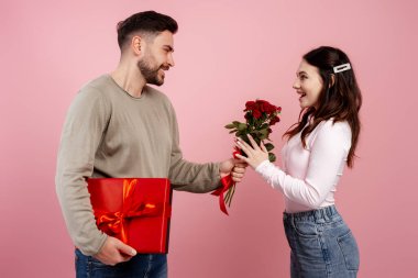 Romantik adam Sevgililer Günü 'nü kutlayan mutlu sevgiliye kırmızı güller ve hediye veriyor.