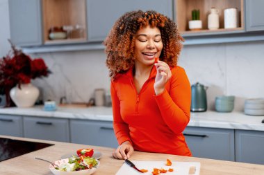 Dengeli bir diyet yemeği için taze ve sağlıklı bir salata hazırlarken genç bir kadın dolma biber tadıyor.
