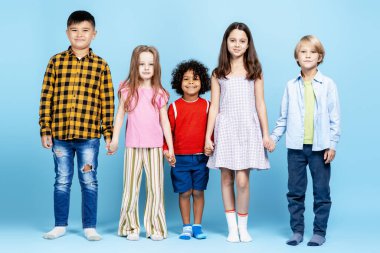 Gülümseyen ve el ele tutuşan, küresel dostluğu ve birliği destekleyen beş çocuktan oluşan çeşitli bir grup.