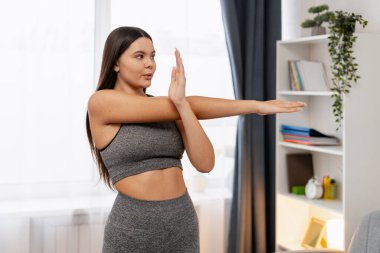 Kadın egzersiz yaparken kolunu esnetiyor, spor yapıyor ve yaşam tarzını geliştiriyor.