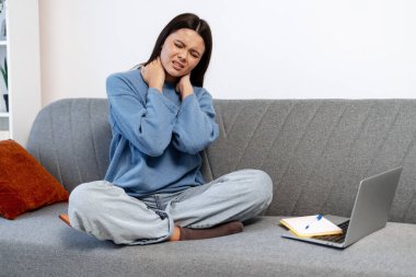 Kadın rahatsız ve yorgun hissediyor, ağrıyan boynunu ve omuzlarını kanepeye sürtüyor.