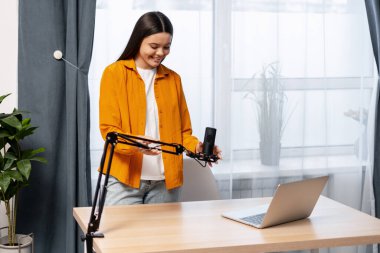 Podcast, canlı yayın ve içerik oluşturma için bir stüdyo mikrofonu kuran genç kadın