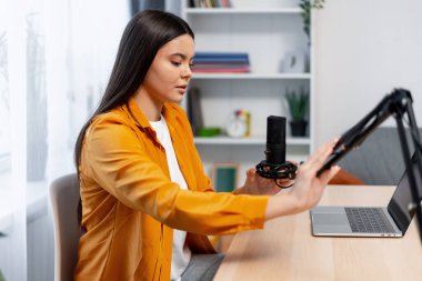 Kadın ev stüdyosundan bir podcast bölümü yaratıyor, profesyonel bir mikrofona konuşuyor - 78 karakter - 