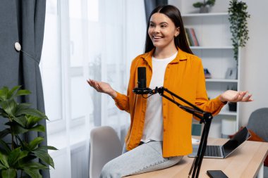 Çevrimiçi yayın, yayın ve dijital içerik oluşturmak için mikrofon ve dizüstü bilgisayar kullanan kadın