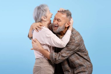 Üst düzey çift yüksek sesle sarılıp gülüyor, aşkı, mutluluğu, emekliliği ve birlikteliği simgeliyor.