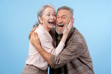 Neşeli yaşlı çift yüksek sesle sarılıp gülüyor, mutluluğu, aşkı ve birlikteliği simgeliyor.