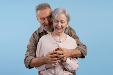 Mutlu son sınıf çifti kucaklıyor, çiçekleri tutuyor, aşkı, aşkı, birlikteliği ve mutluluğu temsil ediyor.