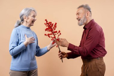 Mutlu son sınıf çifti düşünceli bir kırmızı böğürtlen dalını değiş tokuş ediyor, sevgi ve özen gösteriyorlar.