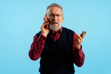 Olgun bir adam cep telefonuyla ciddi bir konuşma yapıyor. Öfke ve jestler gösteriyor.