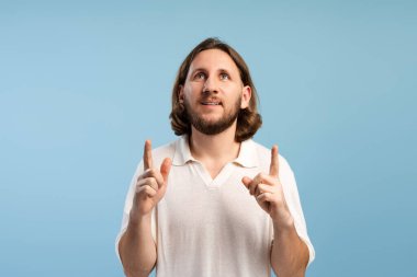 Fikirler üreten, her iki işaret parmağı yukarı doğru gösteren yaratıcı ve ilham verici görünen bir adam.