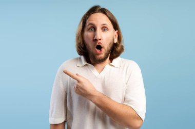 Uzun saçlı ve sakallı bir adam yoğun bir şaşkınlık ve şok yaşıyor. Boş kopya alanını işaret ediyor.