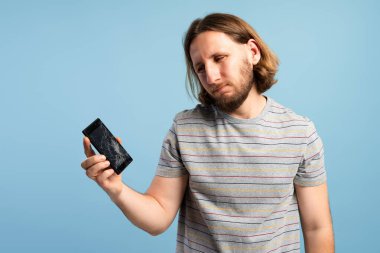 Kazadan sonra kırık bir ekranla bozuk bir akıllı telefonu tutan adam kendini üzgün hissediyor.