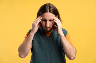 Stres ve baş ağrısı çeken bir adam, güçlü bir rahatsızlık ve baskı hisseder.