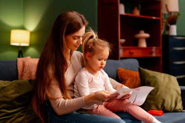 Anne ve kızı birlikte vakit geçiriyorlar, kanepede otururken resim çiziyorlar ve sanat yaratıyorlar.