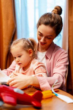 Yaratıcı oyun sırasında küçük çocukları eğiten, aile anlarını ve gelişimi paylaşan genç bir kadın.