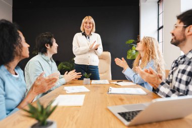 Gülümseyen iş adamları modern ofisin başarısını alkışlıyor. İş konsepti