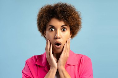 Şaşırmış Afrikalı Amerikalı kadın kameraya açık ağızla bakarken şok edici bir tepki veriyor. Duygu kavramı