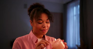 Serene african american woman lighting a scented candle at home for aromatherapy and relaxation