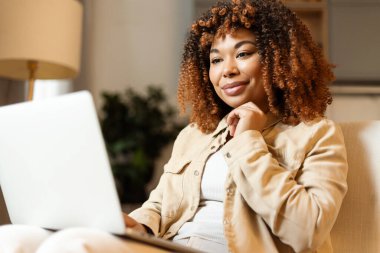 Bilgisayarı kullanan mutlu genç bir kadın ev ofisinden internete bağlanıyor.