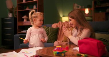 Mutlu anne el çırpıyor ve küçük kızına destek oluyor çizim yapmayı öğreniyor.