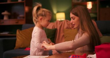 Mutlu anne ve küçük tatlı kız birlikte zaman geçiriyorlar. Sıcak bir oturma odasında çizim yapıyorlar.