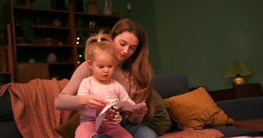 Küçük kızına makas kullanmayı öğreten, boş zamanlarını birlikte geçiren genç bir anne.