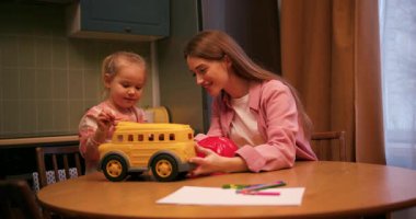 Sevimli kızı ve annesi oyuncak okul otobüsüyle oynuyorlar ve evde beşlik çakıyorlar.