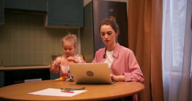 Serbest çalışan annesinin dikkatini dağıtan genç bir kız geceleri mutfaktaki bilgisayarla uğraşıyor.