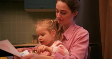 Genç, şefkatli anne renkli kalemlerle çizim yapan küçük tatlı kızıyla kaliteli zaman geçiriyor.