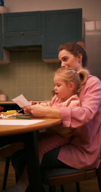 Şefkatli bir anne, küçük kızına mutfak masasında çizim ve yaratıcılık konusunda yardım ediyor.