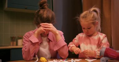 Stresli anne masada ağlarken küçük kızı onu kucaklayıp öperek teselli ediyor.