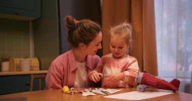 Sevgi dolu anne oyuncaklarla oynarken kızının alnından öpüyor ve el sanatları yapıyor.