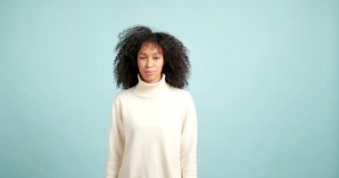 Kıvırcık saçlı, genç Afro-Amerikalı kadın ifadesini ciddi bir gülümsemeden geniş bir gülümsemeye dönüştürüyor.