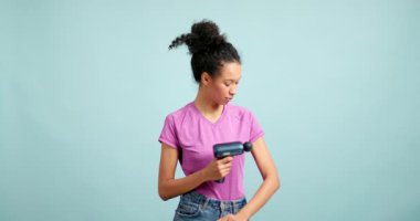 Atletik kadın kolundaki kas ağrısını hafifletmek için elektrikli perküsyon masaj aleti kullanıyor.